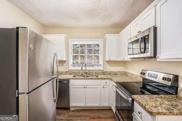 kitchen with stainless steel appliances, white cabinetry, and dark wood-type flooring