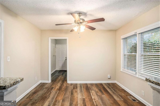 unfurnished room featuring dark hardwood / wood-style floors, ceiling fan, and a textured ceiling