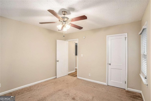 unfurnished bedroom featuring ceiling fan, light colored carpet, and a textured ceiling