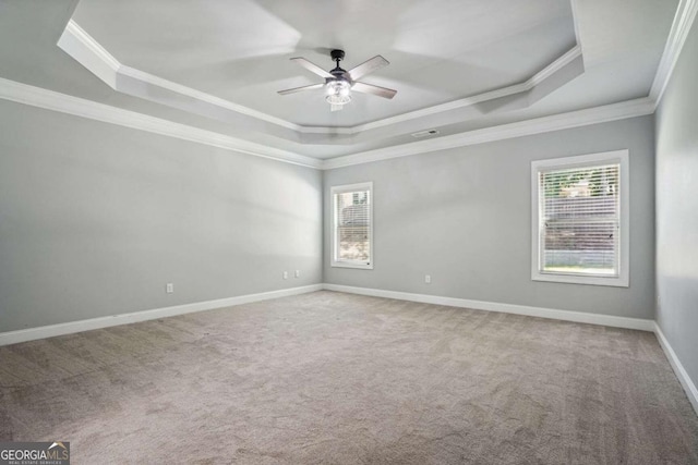 carpeted spare room with a tray ceiling, ceiling fan, and ornamental molding