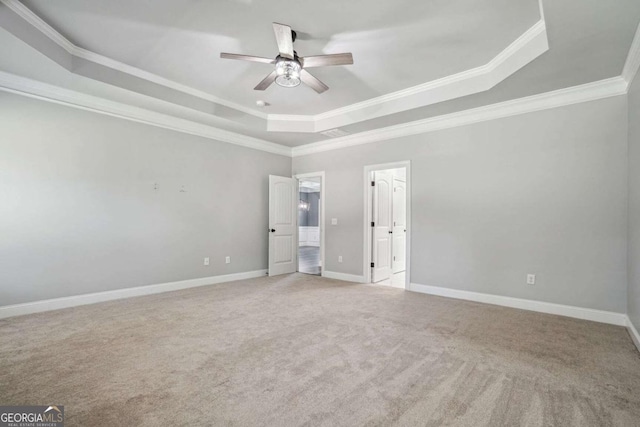 carpeted empty room with ceiling fan, a raised ceiling, and ornamental molding