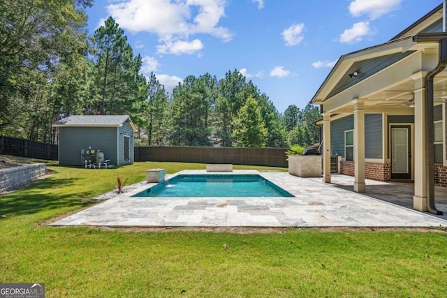 view of swimming pool with a lawn, ceiling fan, pool water feature, an outbuilding, and a patio