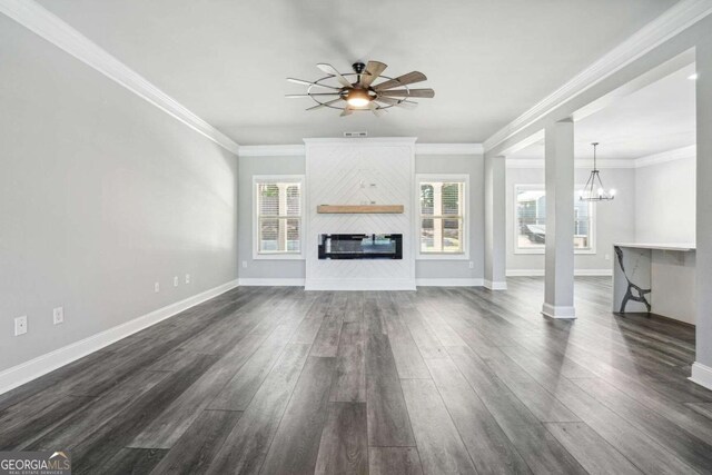 unfurnished living room with ceiling fan with notable chandelier, a large fireplace, dark hardwood / wood-style floors, and ornamental molding
