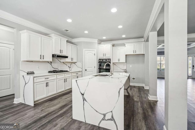 kitchen featuring light stone countertops, a center island with sink, white cabinetry, and dark hardwood / wood-style floors