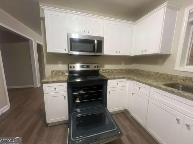 kitchen with light stone counters, dark hardwood / wood-style floors, white cabinetry, and sink