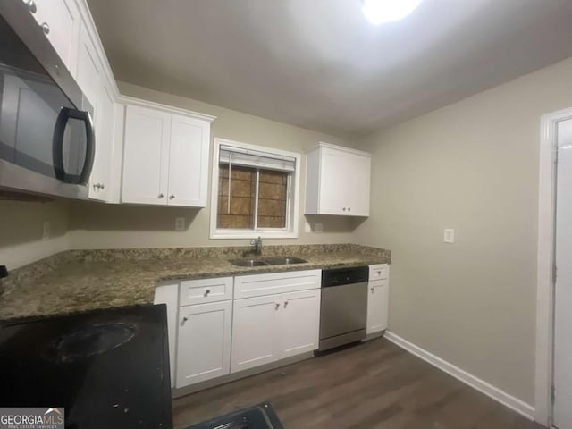 kitchen featuring white cabinetry, sink, stainless steel appliances, dark hardwood / wood-style floors, and dark stone counters