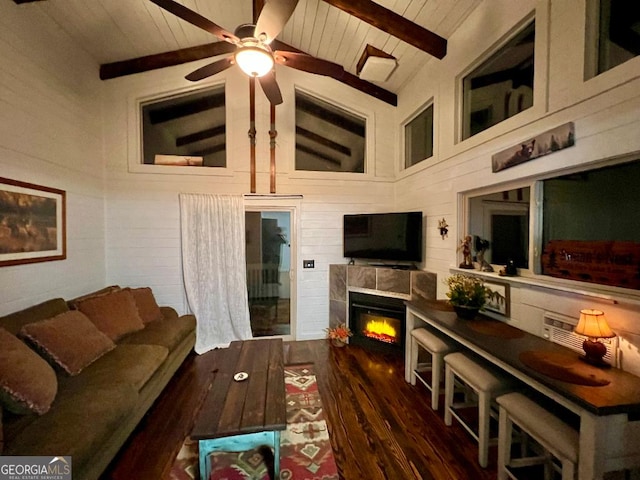 living room with ceiling fan, dark wood-type flooring, wooden ceiling, beamed ceiling, and a tiled fireplace