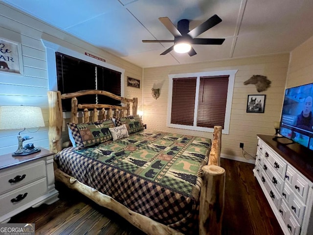 bedroom with ceiling fan, dark hardwood / wood-style flooring, and wooden walls