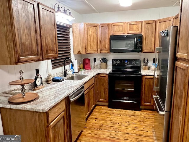 kitchen with black appliances, light hardwood / wood-style floors, and sink