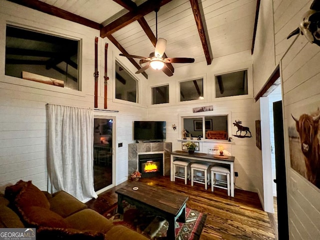 living room featuring beam ceiling, dark hardwood / wood-style floors, ceiling fan, and a tiled fireplace