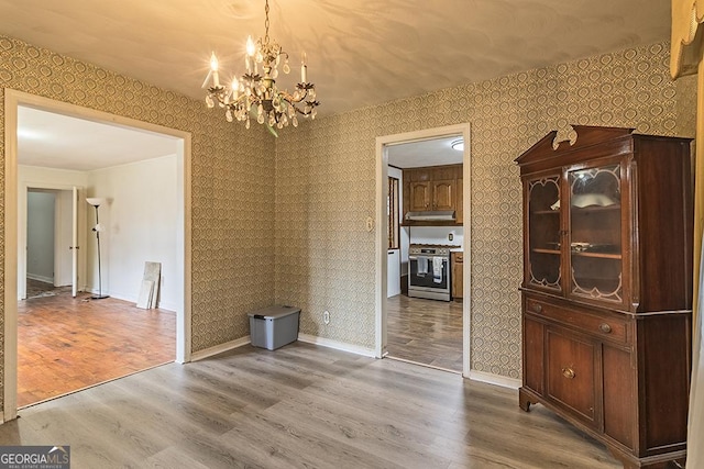 unfurnished dining area with hardwood / wood-style floors and an inviting chandelier