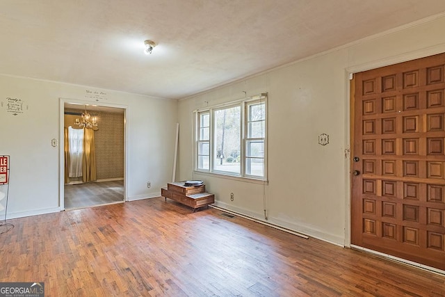 foyer entrance featuring a notable chandelier, wood-type flooring, and ornamental molding