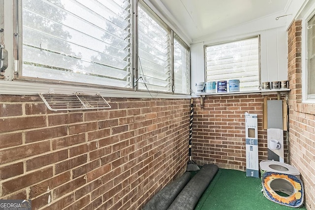 exterior space featuring lofted ceiling and brick wall