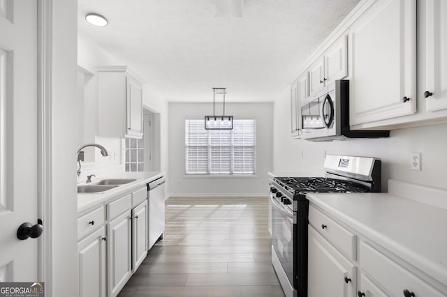 kitchen featuring white cabinetry, sink, stainless steel appliances, and pendant lighting