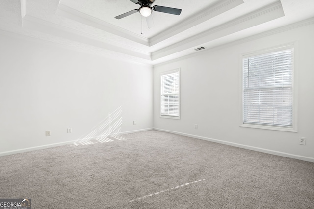 carpeted empty room featuring ceiling fan, ornamental molding, and a raised ceiling