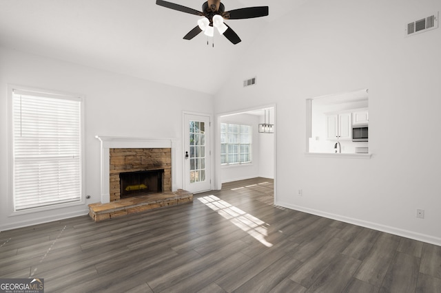 unfurnished living room featuring ceiling fan, a stone fireplace, high vaulted ceiling, and dark wood-type flooring