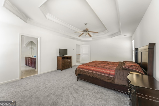 bedroom with light carpet, a raised ceiling, ensuite bath, and ceiling fan