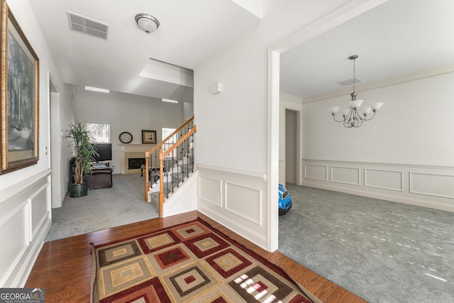 foyer featuring dark hardwood / wood-style flooring, an inviting chandelier, and crown molding