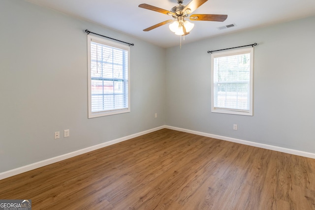 spare room featuring wood-type flooring, ceiling fan, and a healthy amount of sunlight