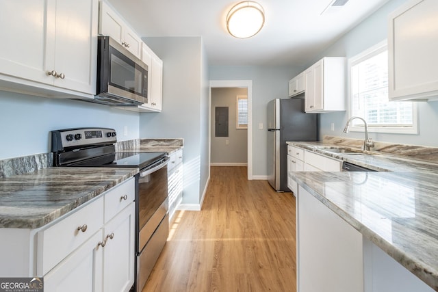 kitchen featuring light stone countertops, light wood-type flooring, stainless steel appliances, sink, and white cabinetry