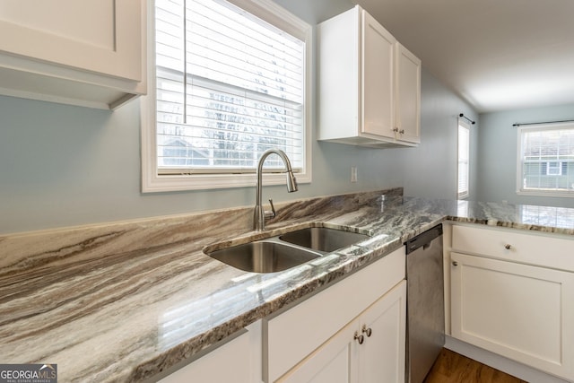 kitchen featuring a wealth of natural light, sink, dishwasher, and light stone countertops