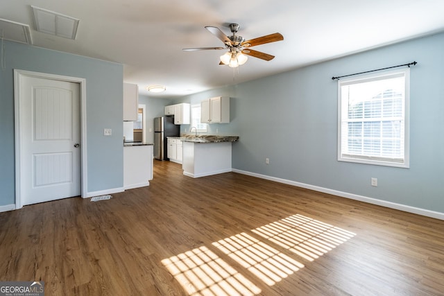 unfurnished living room with ceiling fan, sink, and hardwood / wood-style flooring