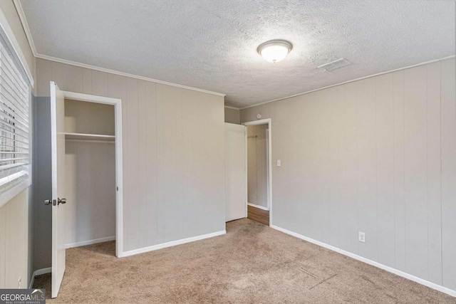 unfurnished bedroom featuring light colored carpet, a closet, crown molding, and wood walls