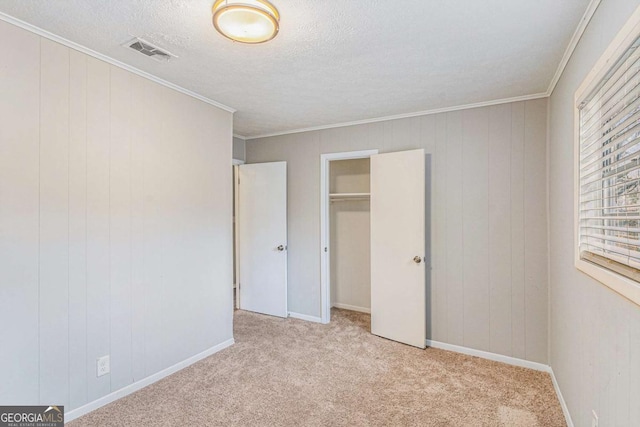 unfurnished bedroom with light carpet, a textured ceiling, a closet, and ornamental molding