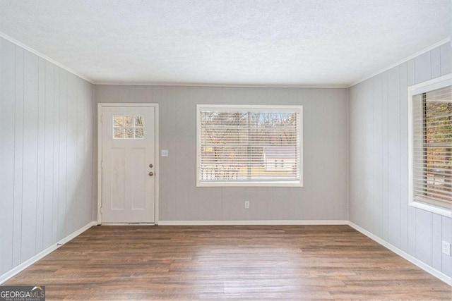 foyer with wood walls, a healthy amount of sunlight, a textured ceiling, and hardwood / wood-style flooring