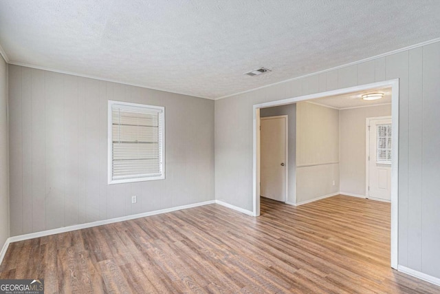 spare room with crown molding, hardwood / wood-style floors, and a textured ceiling