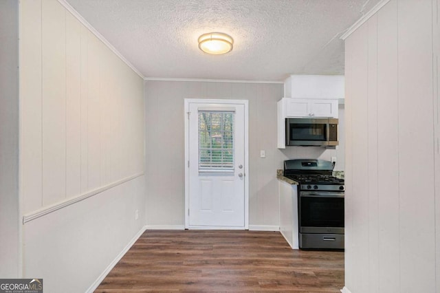 kitchen with a textured ceiling, stainless steel appliances, crown molding, dark hardwood / wood-style floors, and white cabinetry