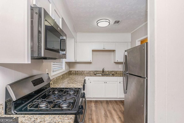 kitchen with white cabinetry, sink, light hardwood / wood-style floors, and appliances with stainless steel finishes