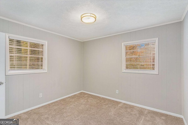 spare room with light carpet, crown molding, a textured ceiling, and wooden walls