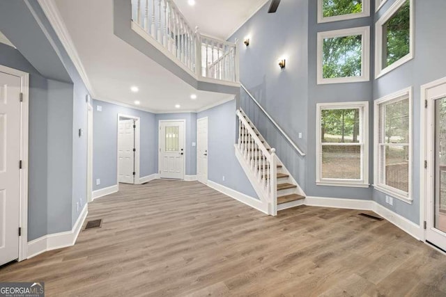 entryway featuring hardwood / wood-style floors, a towering ceiling, and ornamental molding