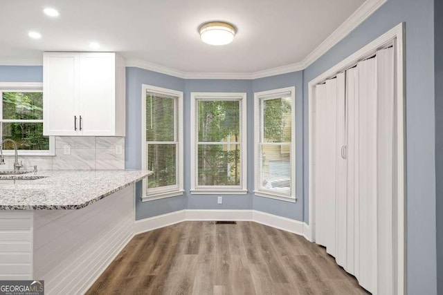 unfurnished dining area with light wood-type flooring, ornamental molding, and sink