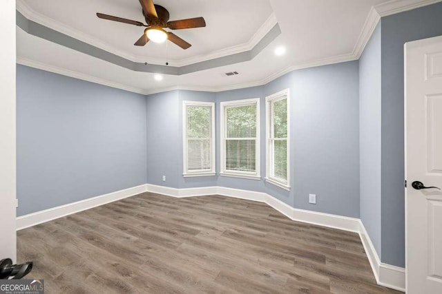 spare room with a raised ceiling, ceiling fan, hardwood / wood-style floors, and ornamental molding