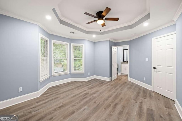 unfurnished bedroom with ceiling fan, light wood-type flooring, ornamental molding, and a tray ceiling