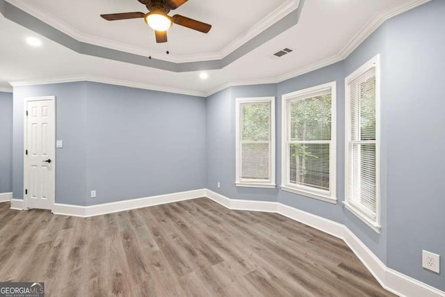 unfurnished room with hardwood / wood-style flooring, ceiling fan, crown molding, and a tray ceiling