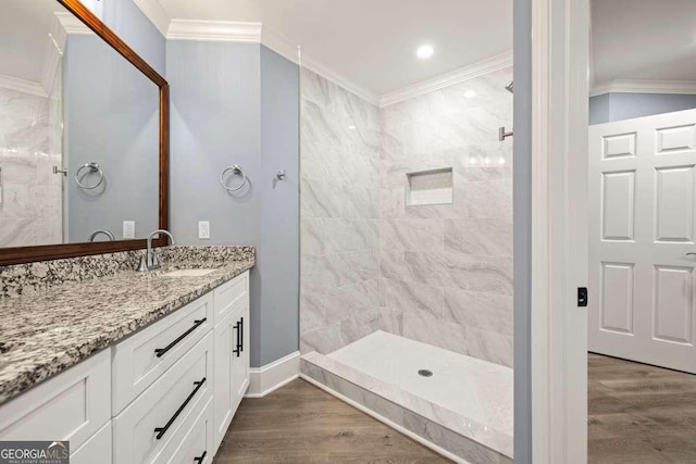 bathroom featuring crown molding, hardwood / wood-style floors, vanity, and tiled shower