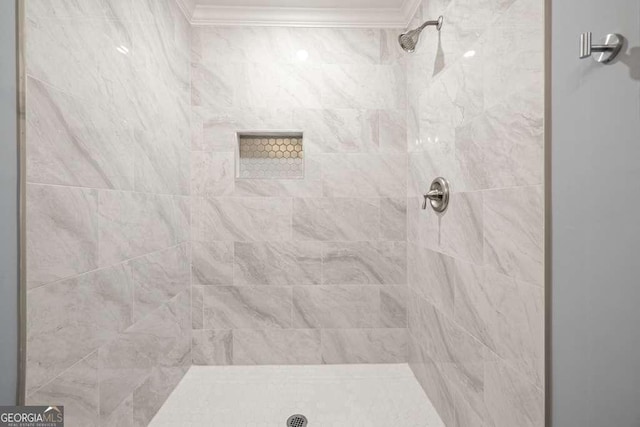 bathroom with crown molding and tiled shower