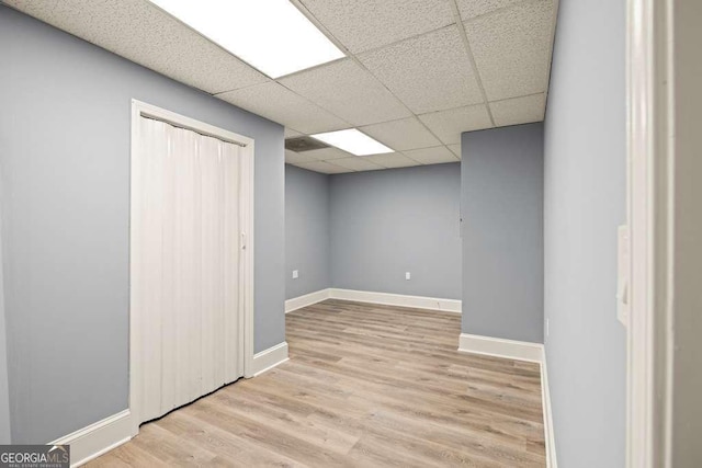 basement featuring a drop ceiling and light hardwood / wood-style floors