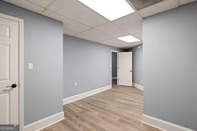 basement featuring a drop ceiling and light hardwood / wood-style floors