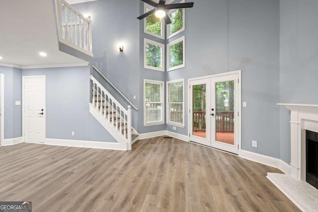 unfurnished living room featuring hardwood / wood-style floors, plenty of natural light, a high ceiling, and french doors