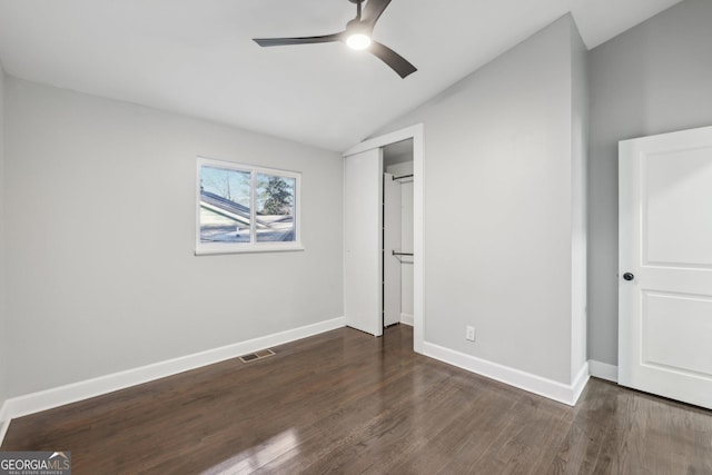 unfurnished bedroom with ceiling fan, a closet, dark hardwood / wood-style flooring, and vaulted ceiling