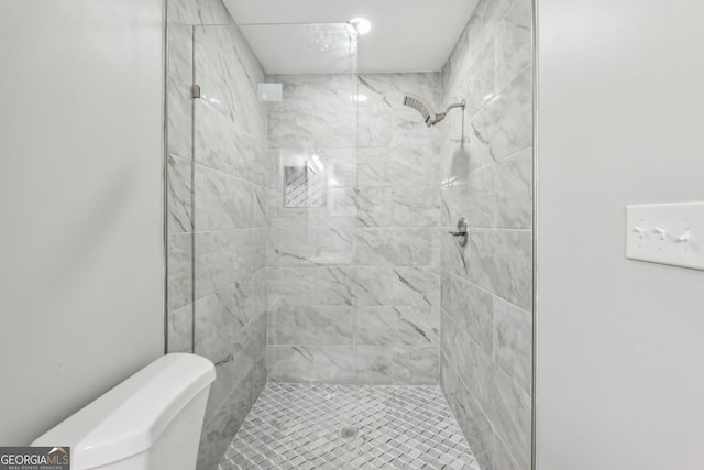 bathroom featuring toilet and a tile shower