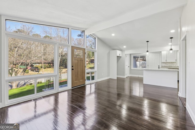 unfurnished living room with vaulted ceiling with beams and dark wood-type flooring