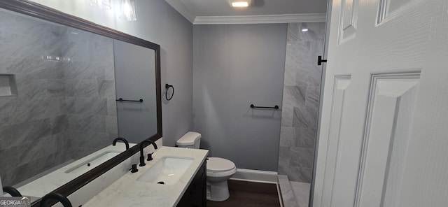 bathroom with tiled shower, crown molding, vanity, and toilet