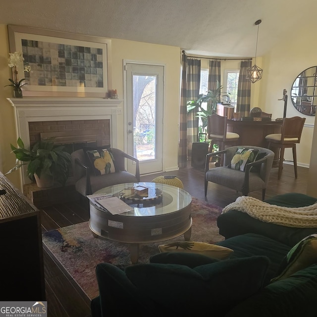 living room with a fireplace, dark hardwood / wood-style flooring, and a textured ceiling