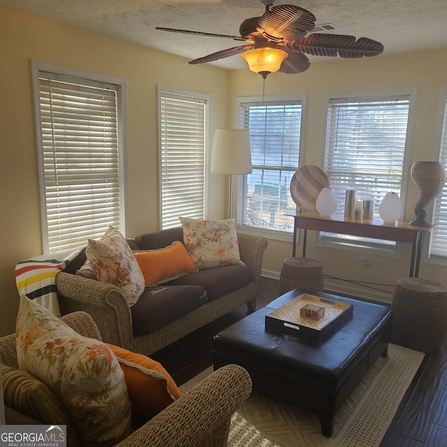 living room with ceiling fan, wood-type flooring, and a textured ceiling