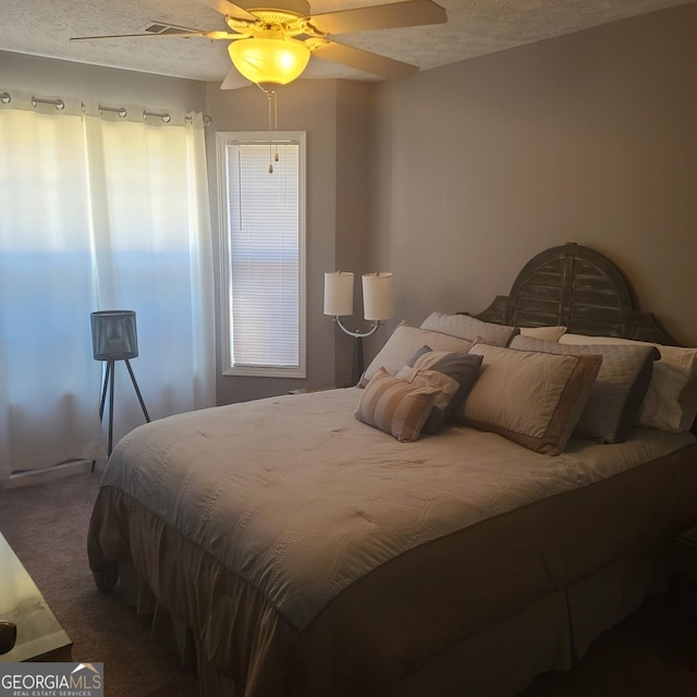 carpeted bedroom featuring ceiling fan and a textured ceiling